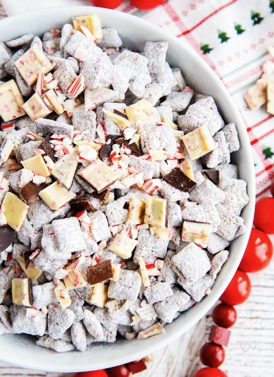 A bowl of Peppermint Bark Puppy Chow topped with square pieces of Peppermint Bark candy .