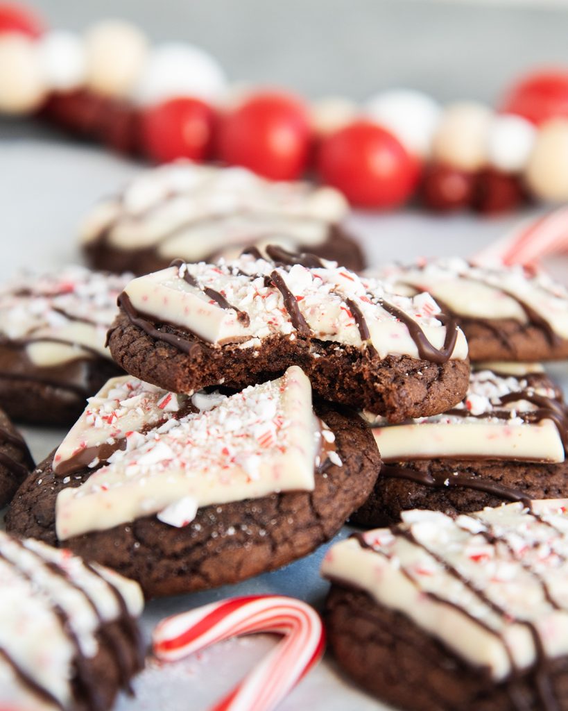 A stack of peppermint brownie cookies, one has a bite out of it.