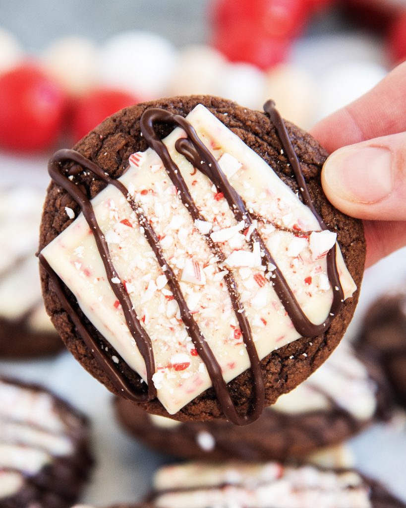 A hand holding a peppermint bark topped brownie cookie.