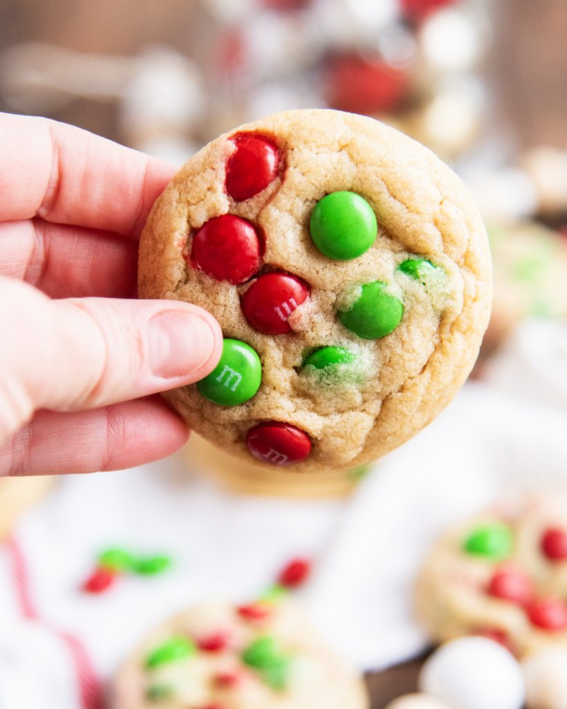 A hand holding a Christmas M&m cookie.
