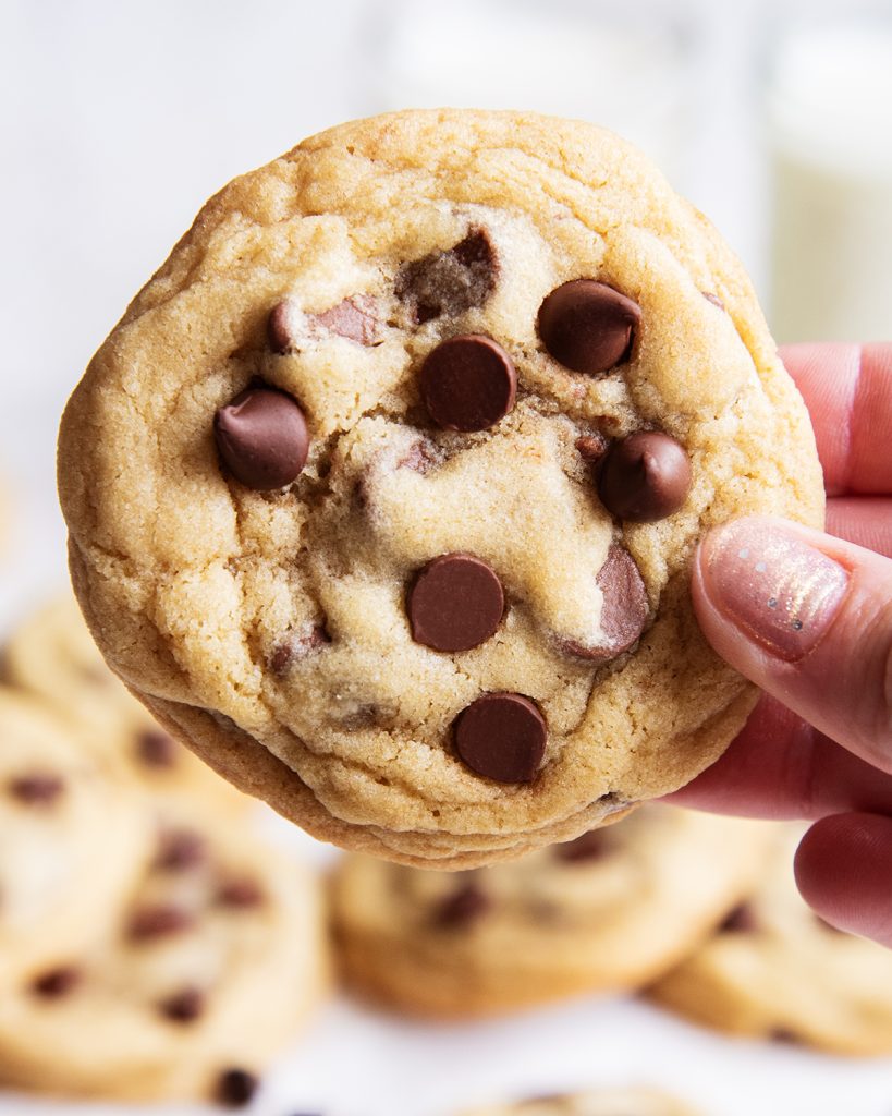 A hand holding a chocolate chip cookie.