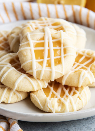 A close up of plate of lemon thumbprint cookies with icing drizzled over the top.