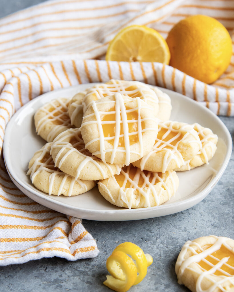 A plate of lemon thumbprint cookies with icing drizzled over the top.