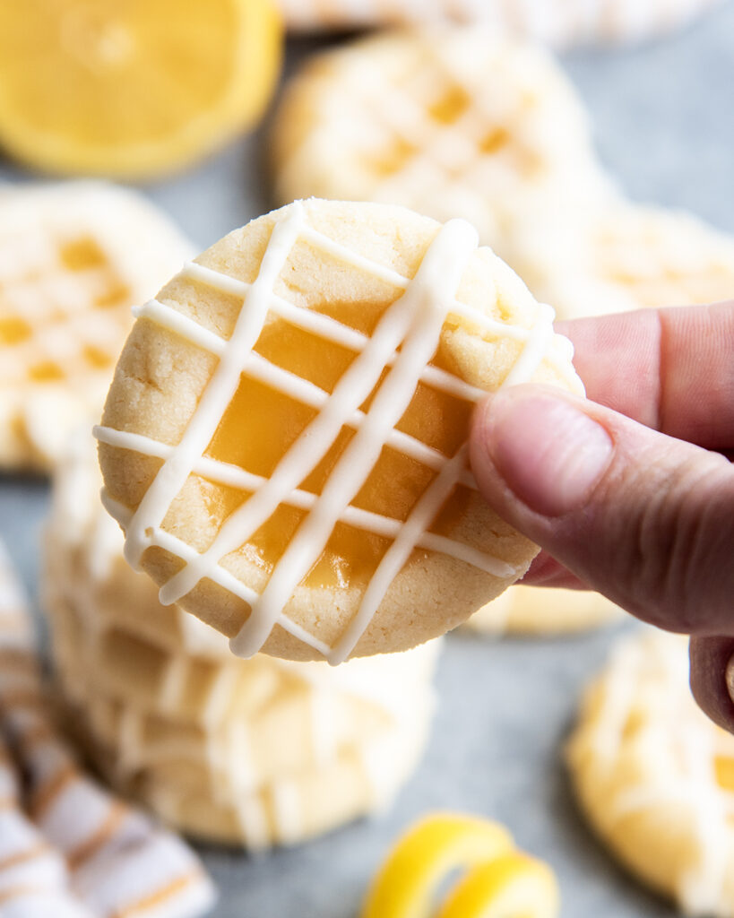 A hand holding a lemon curd cookie with a lemon curd center.