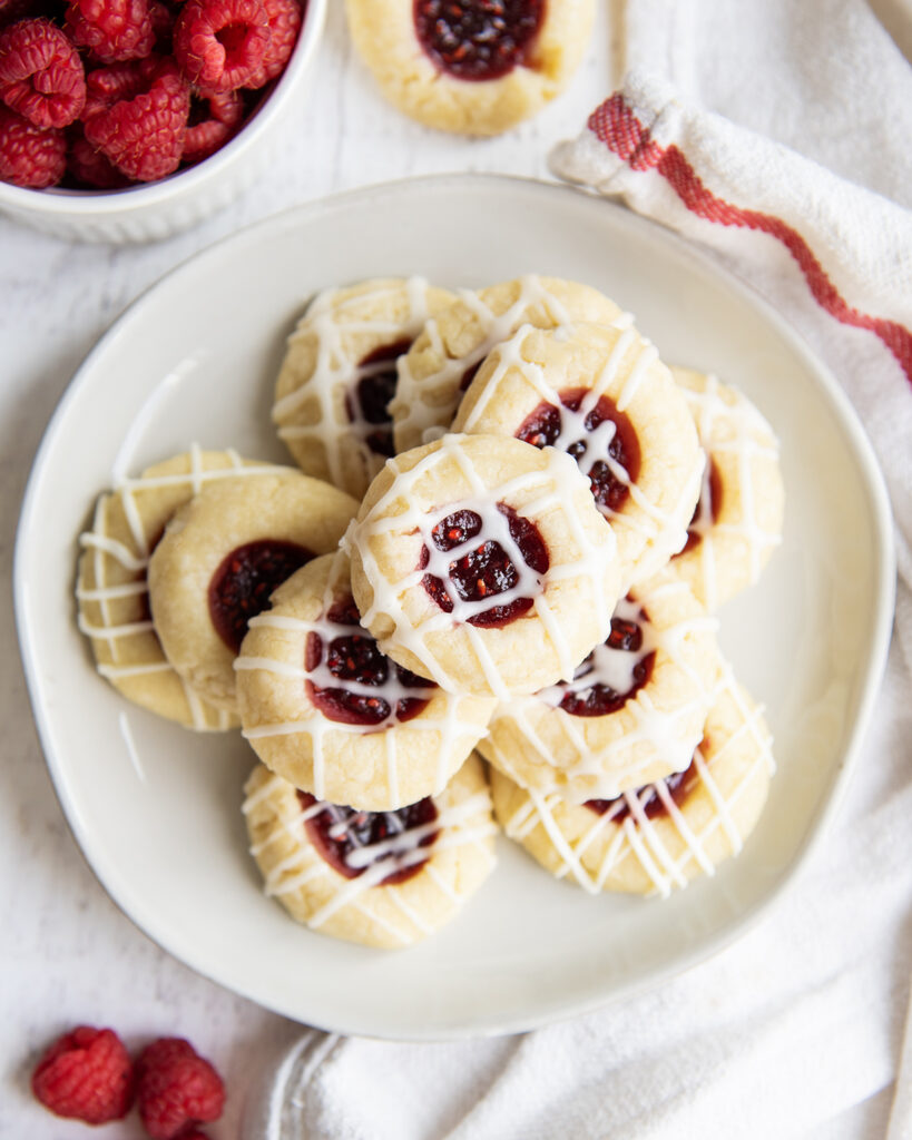 An overhead photo of a plate of a pile of Raspberry thumbprint cookies.