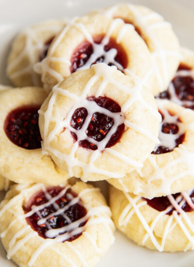 A close up of a pile of raspberry jam thumbprint cookies.