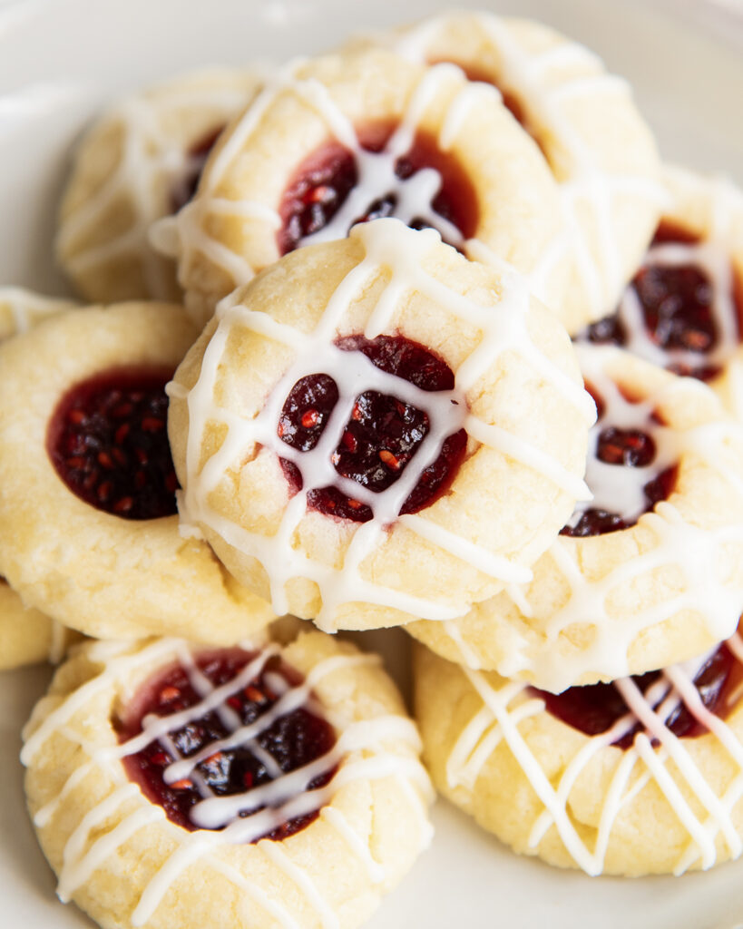 A close up of a pile of raspberry jam thumbprint cookies.