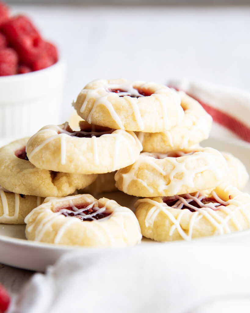 A pile of thumbprint cookies on a white plate.