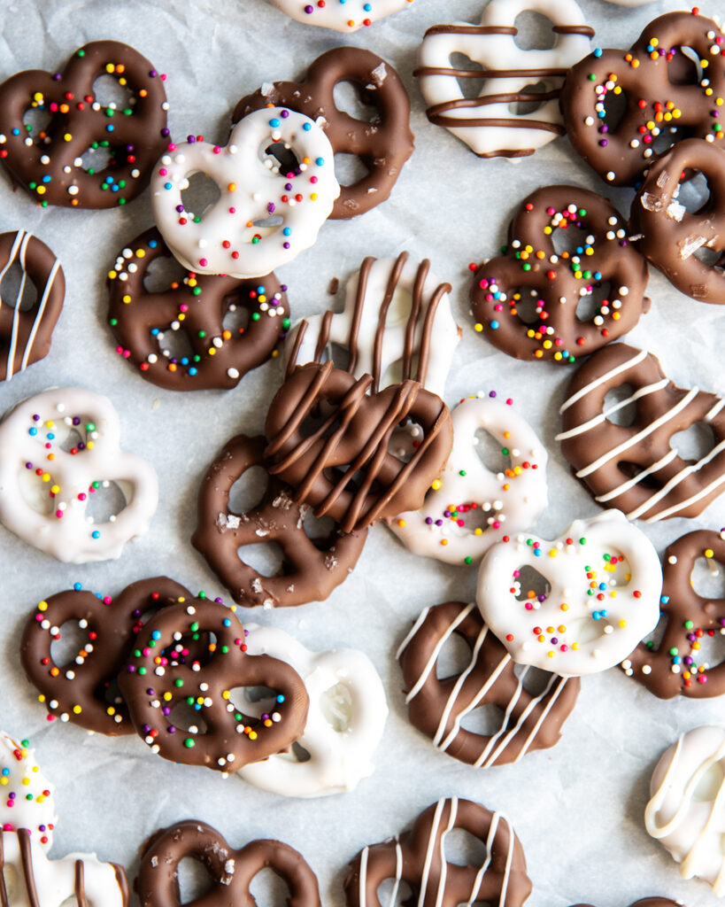 Chocolate covered pretzels topped with small round sprinkles, and drizzled with chocolate.