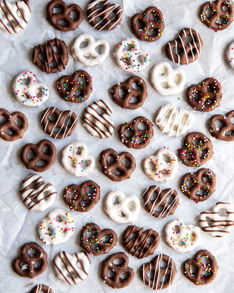 An above view of white chocolate and milk chocolate covered pretzels on a piece of parchment paper.