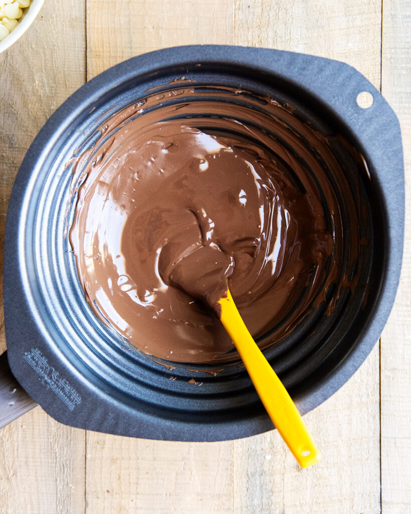 Chocolate in a double boiler with a rubber spatula. 