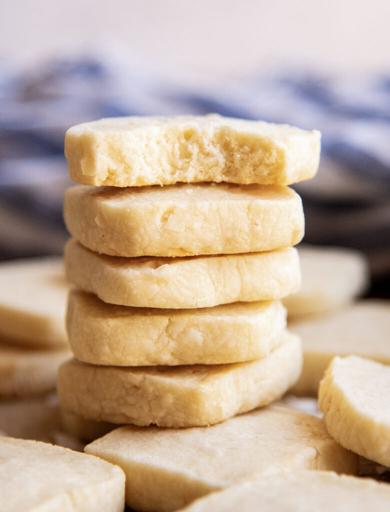 A stack of coconut shortbread cookies, and the top cookie has a bite out of it.