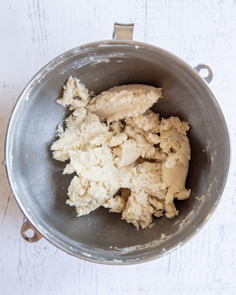 An above photo of raw cookie dough in a silver mixing bowl.