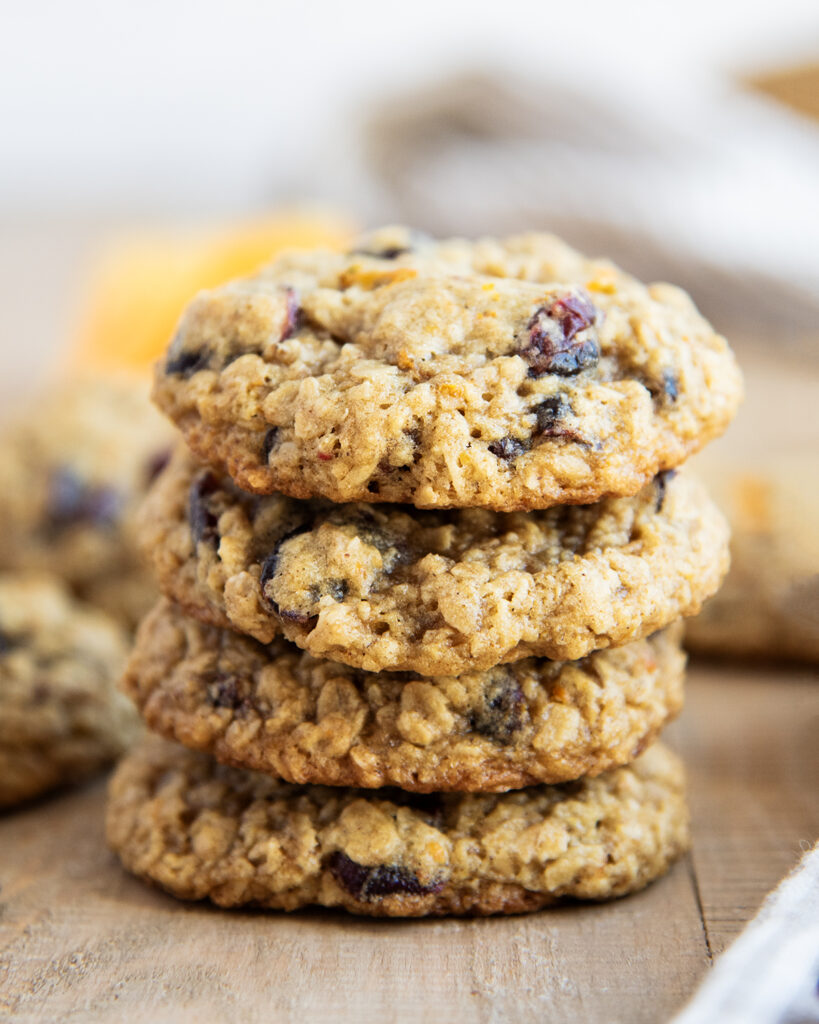 A stack of 4 cranberry oatmeal cookies on a wooden table.