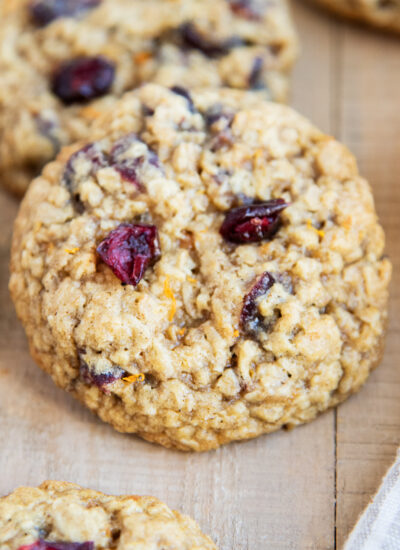 An oatmeal cranberry orange cookie on a wooden table.