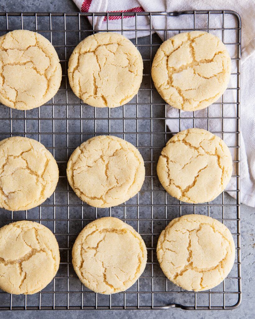 An overhead photo of a cooling rack topped with rows of round crinkly sugar cookies.