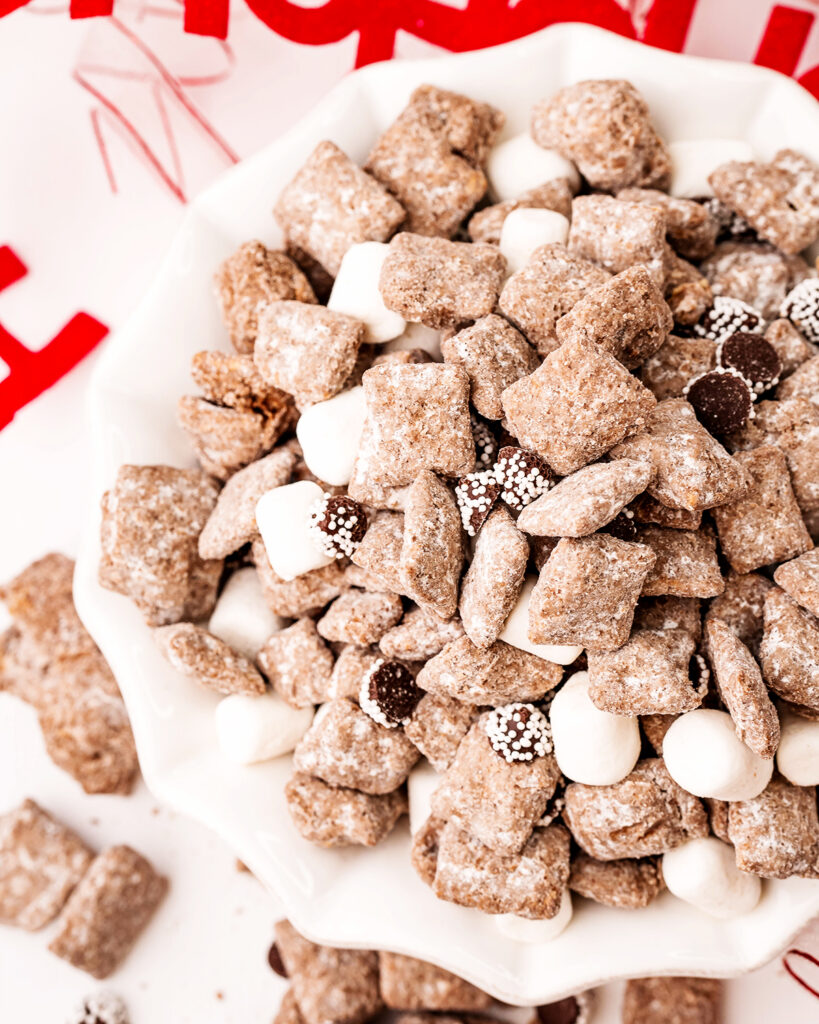 A bowl of hot chocolate muddy buddies, mixed with mini marshmallows and candies.