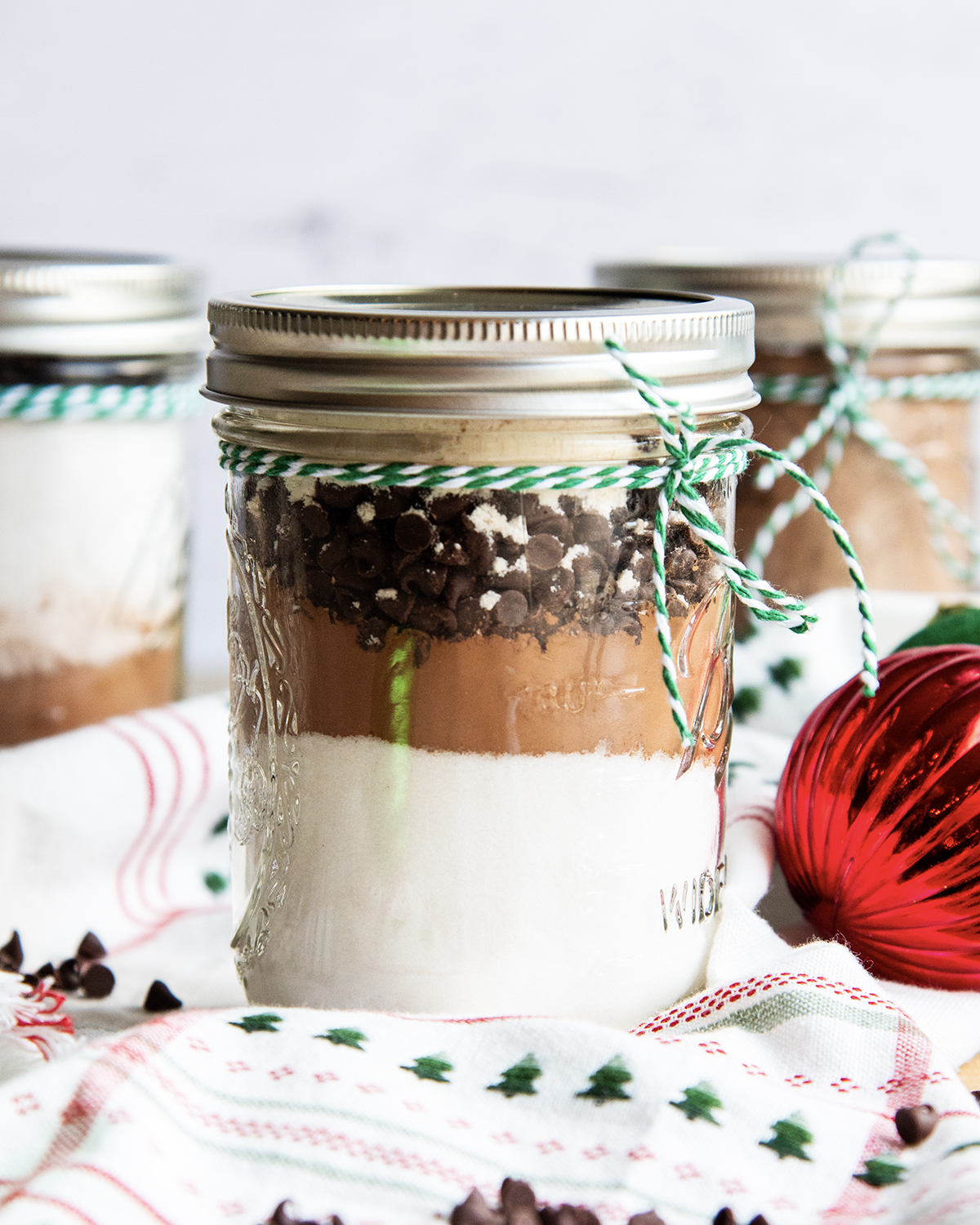 A mason jar full of layered ingredients, with granulated sugar, cocoa powder, and chocolate chips.