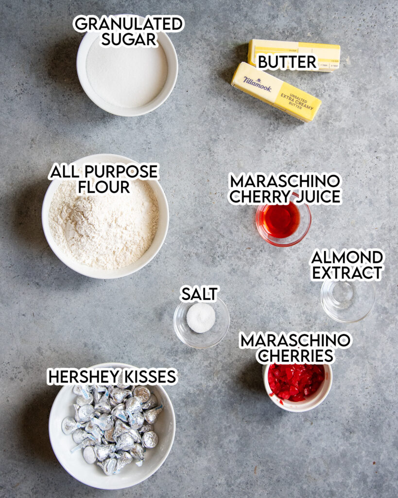 The ingredients needed to make cherry kiss cookies, like granulated sugar, all purpose flour, maraschino cherries, and Hershey Kisses.