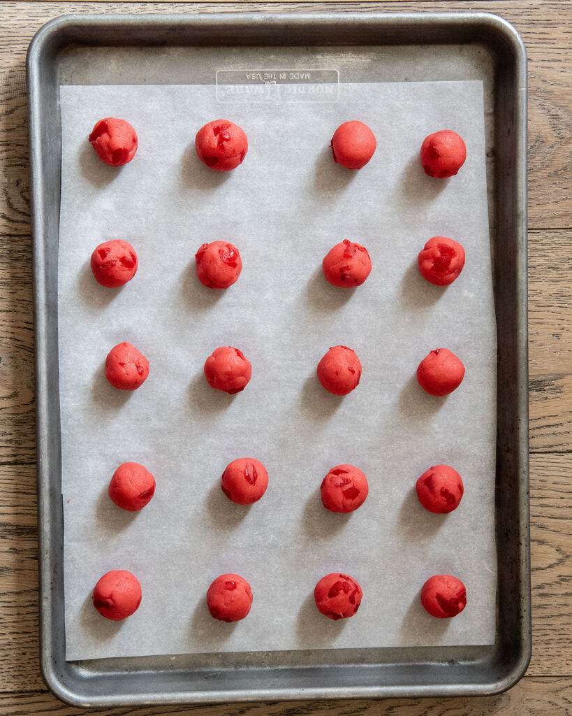 Rolled cookie dough balls in rows on a cookie sheet.