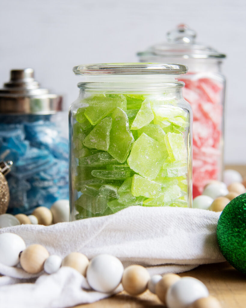 A clear glass jar full of green pieces of hard candy.