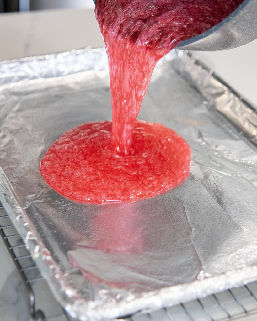 Liquid candy pouring onto a baking pan lined with aluminum foil.
