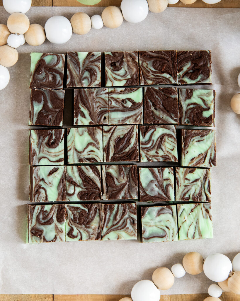 Squares of mint chocolate fudge on a piece of parchment paper.