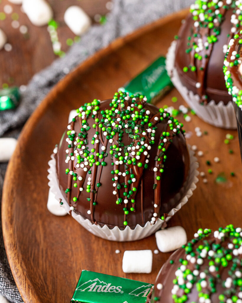 A chocolate sphere topped with green and white sprinkles.