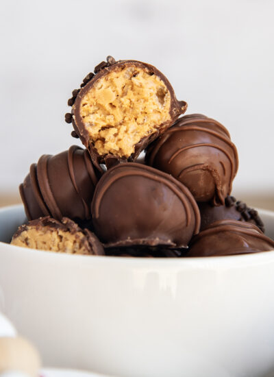 A close up of a stack of peanut butter rice crispy balls in a white bowl.
