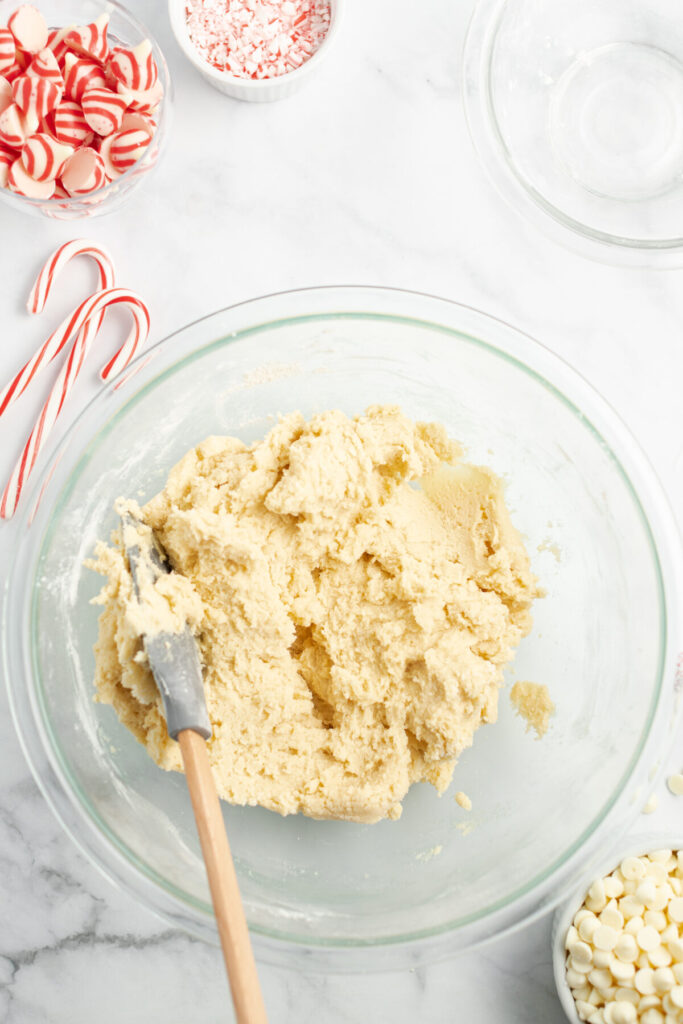 An above view of a bowl of sugar cookie dough with a rubber spatula in it.