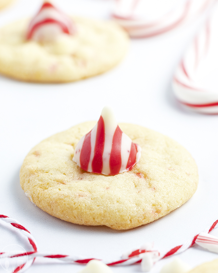 A close up of a Peppermint Blossom cookie topped with a red and white striped Candy Cane Kiss.
