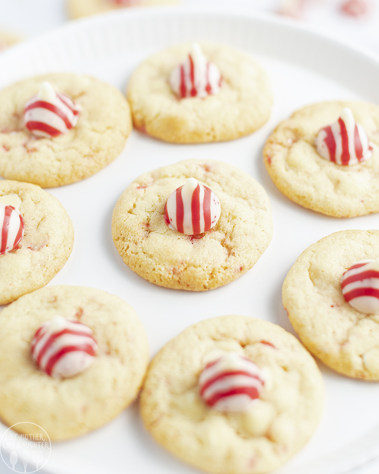 A plate of peppermint kiss cookies, each topped with a red and white striped candy Kiss.