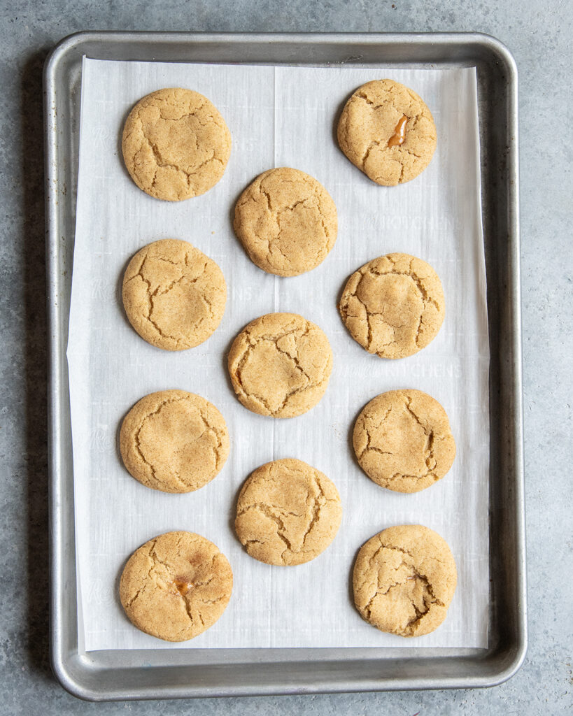 A cookie sheet topped with caramel stuffed snickerdoodles.