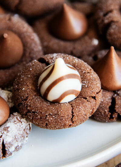 A close up of a chocolate blossom cookie topped with a Hershey's white chocolate Hug candy.