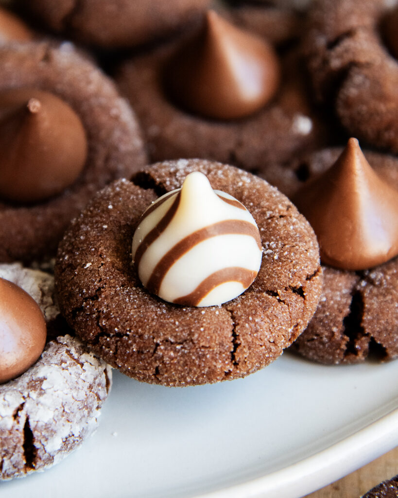 A close up of a chocolate blossom cookie topped with a Hershey's white chocolate Hug candy. 