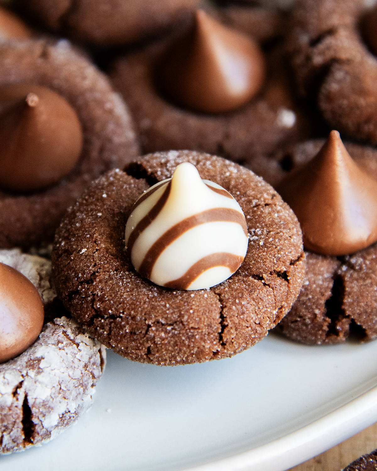 A close up of a chocolate blossom cookie topped with a Hershey's white chocolate Hug candy.