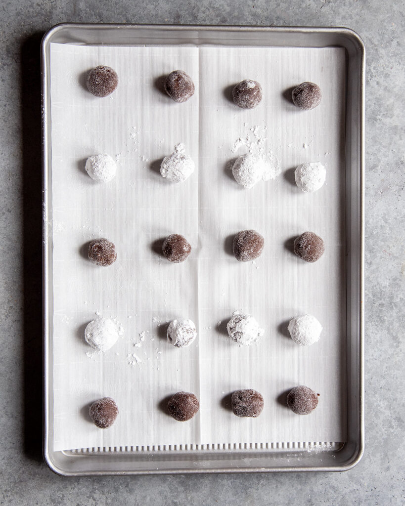 A pan of cookie balls rolled in granulated sugar and powdered sugar.