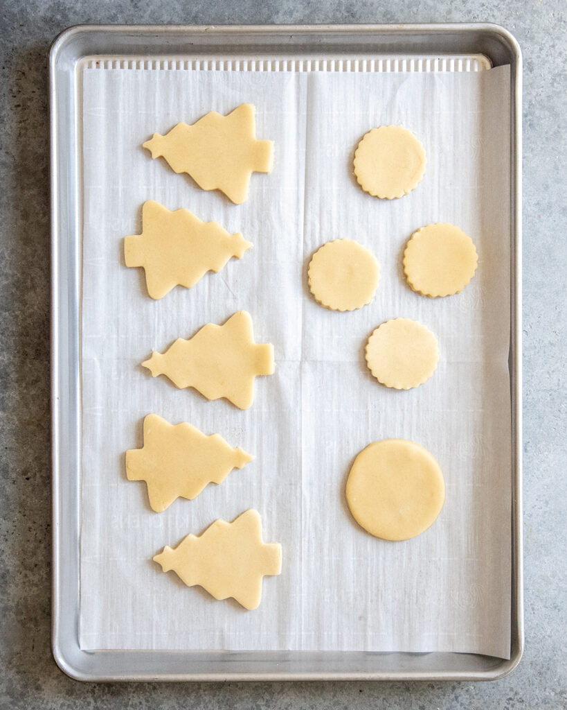 A cookie sheet topped with cut out sugar cookie dough.