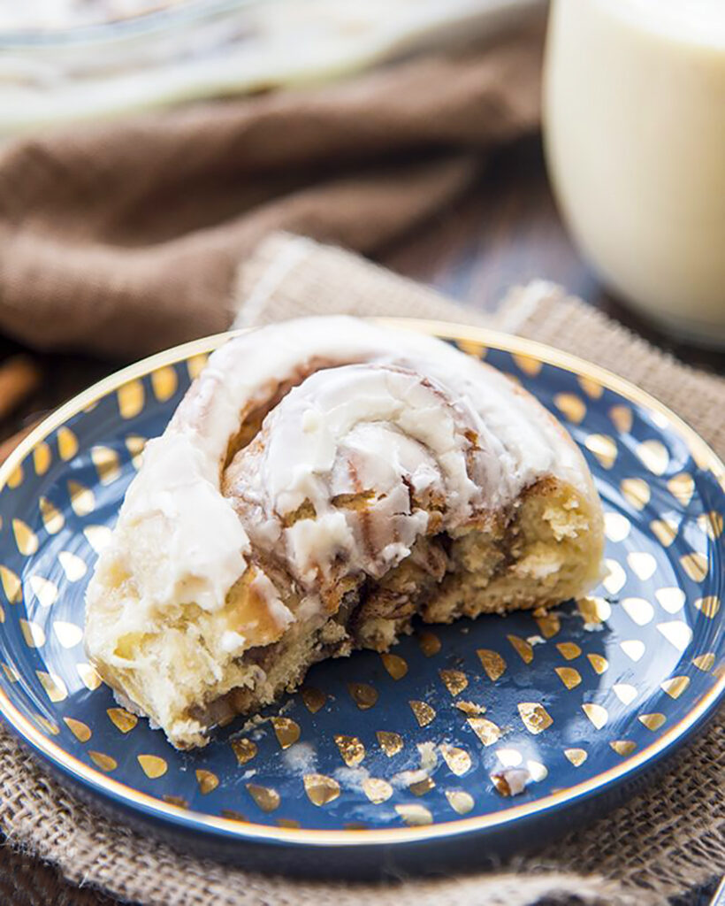 Half an eggnog cinnamon roll on a blue plate.