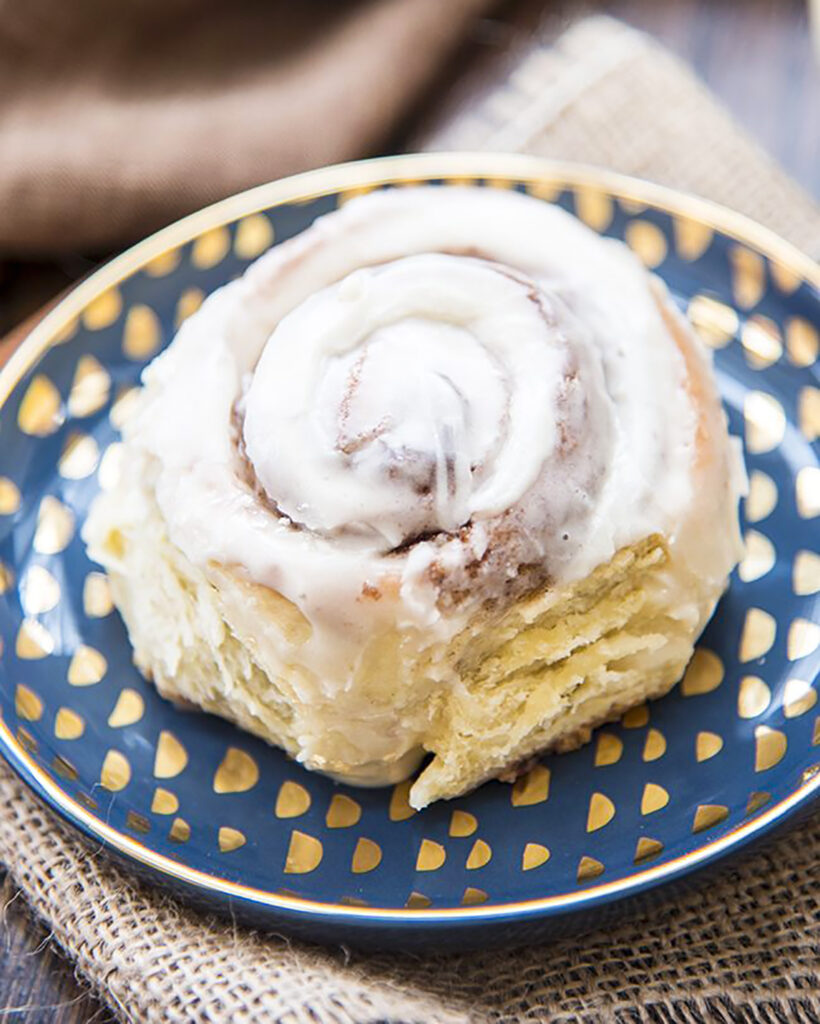 A close up of an eggnog sweet roll with icing on top. 