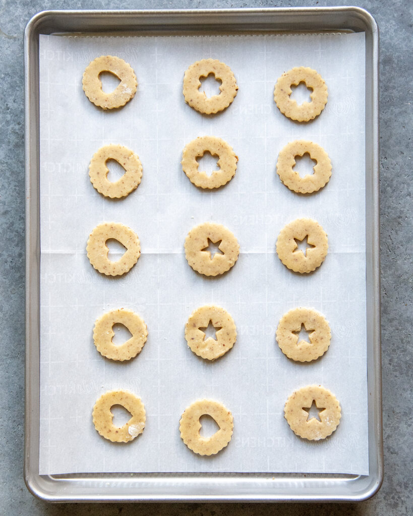 Unbaked cut out linzer cookies on a cookie sheet.