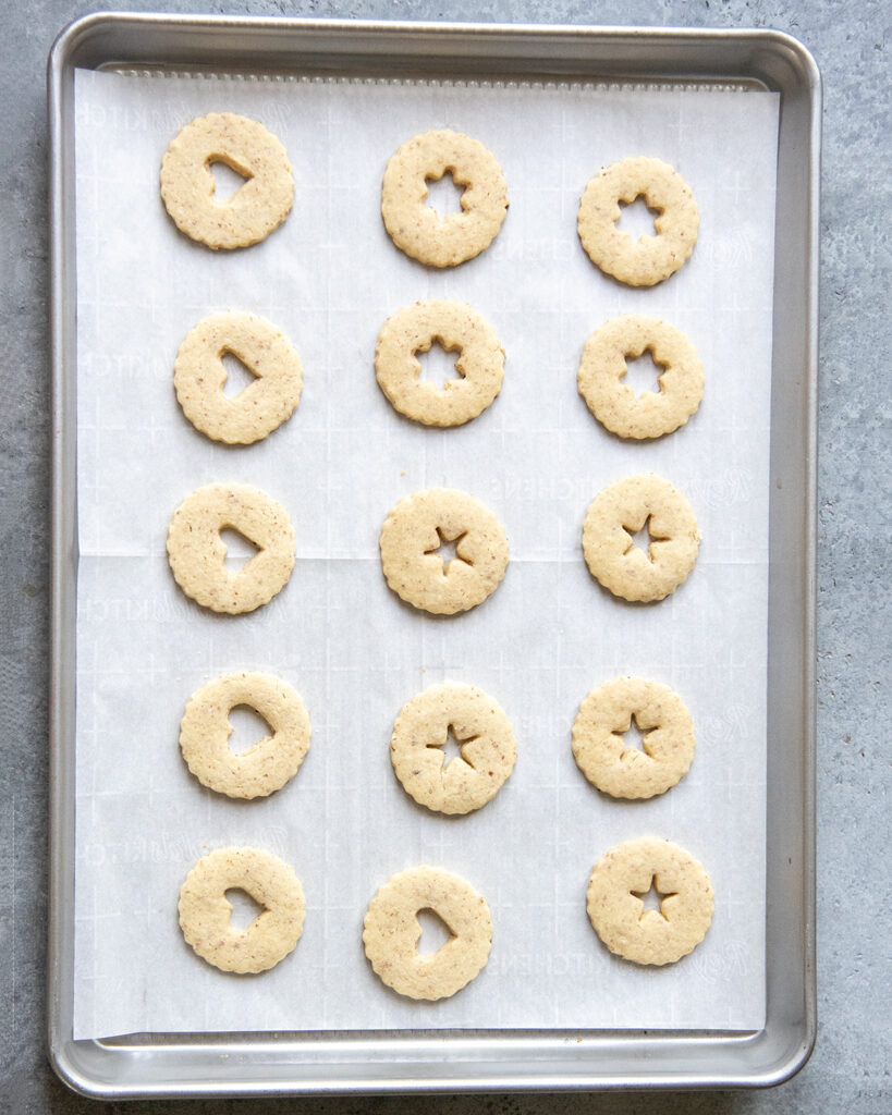 Baked cut out linzer cookies on a cookie sheet.