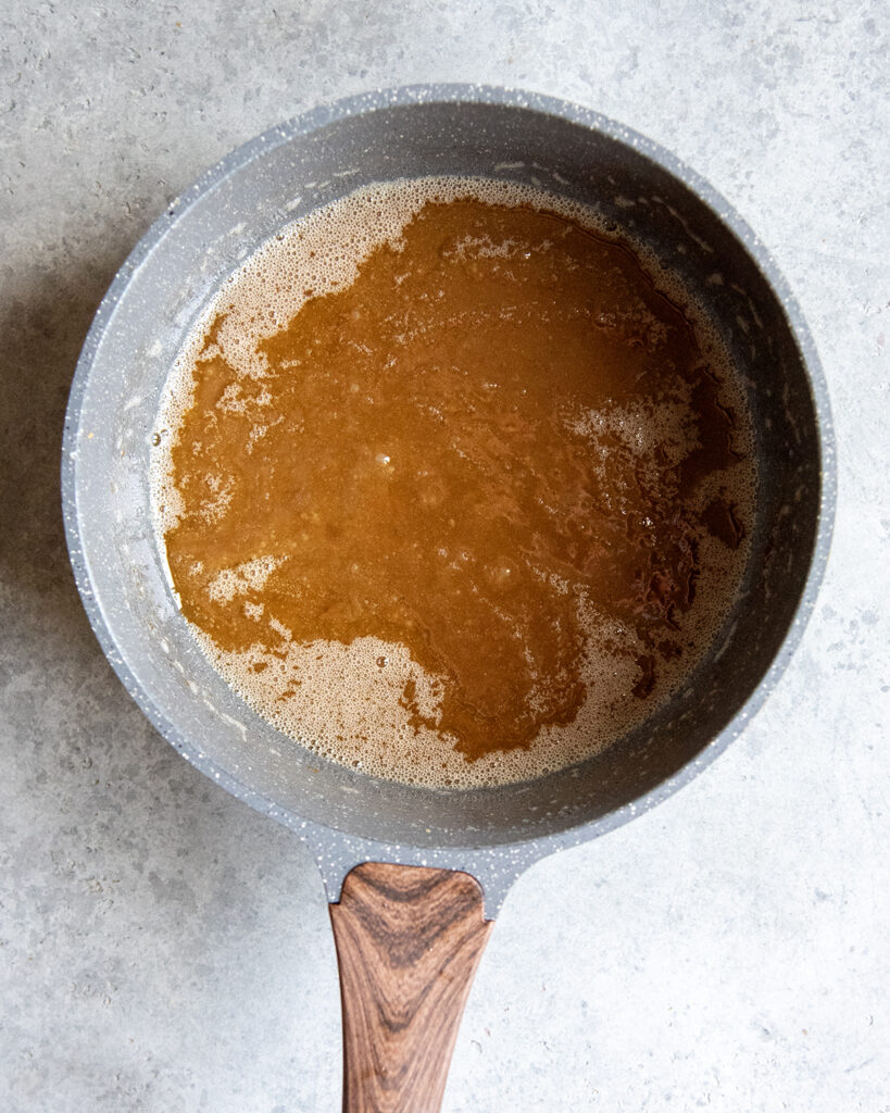 A sauce pan with melted butter and sugar in it.