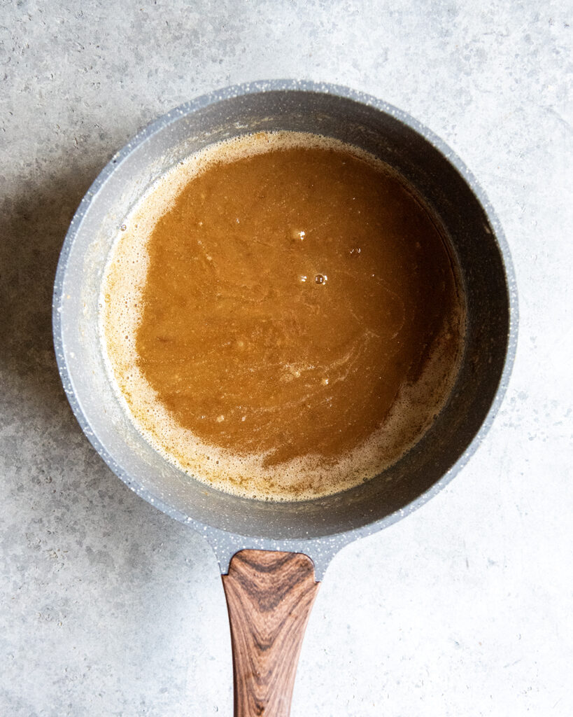 A sauce pan full of a brown caramel colored mixture. 