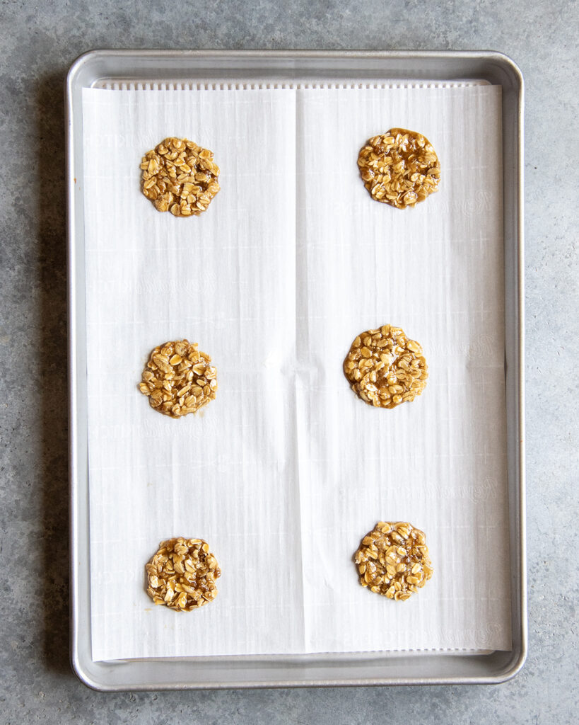 Uncooked oatmeal lace cookies on a cooking sheet .