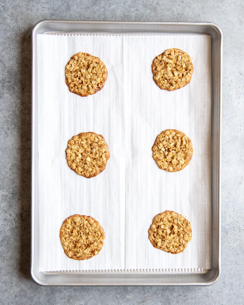 Oatmeal lace cookies on a lined cookie sheet.