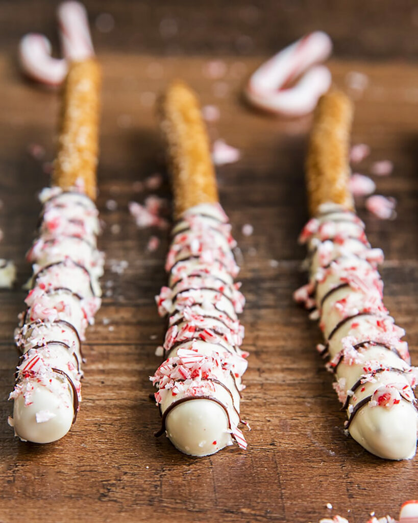 Pretzel rods dipped in white chocolate and topped with candy cane pieces.