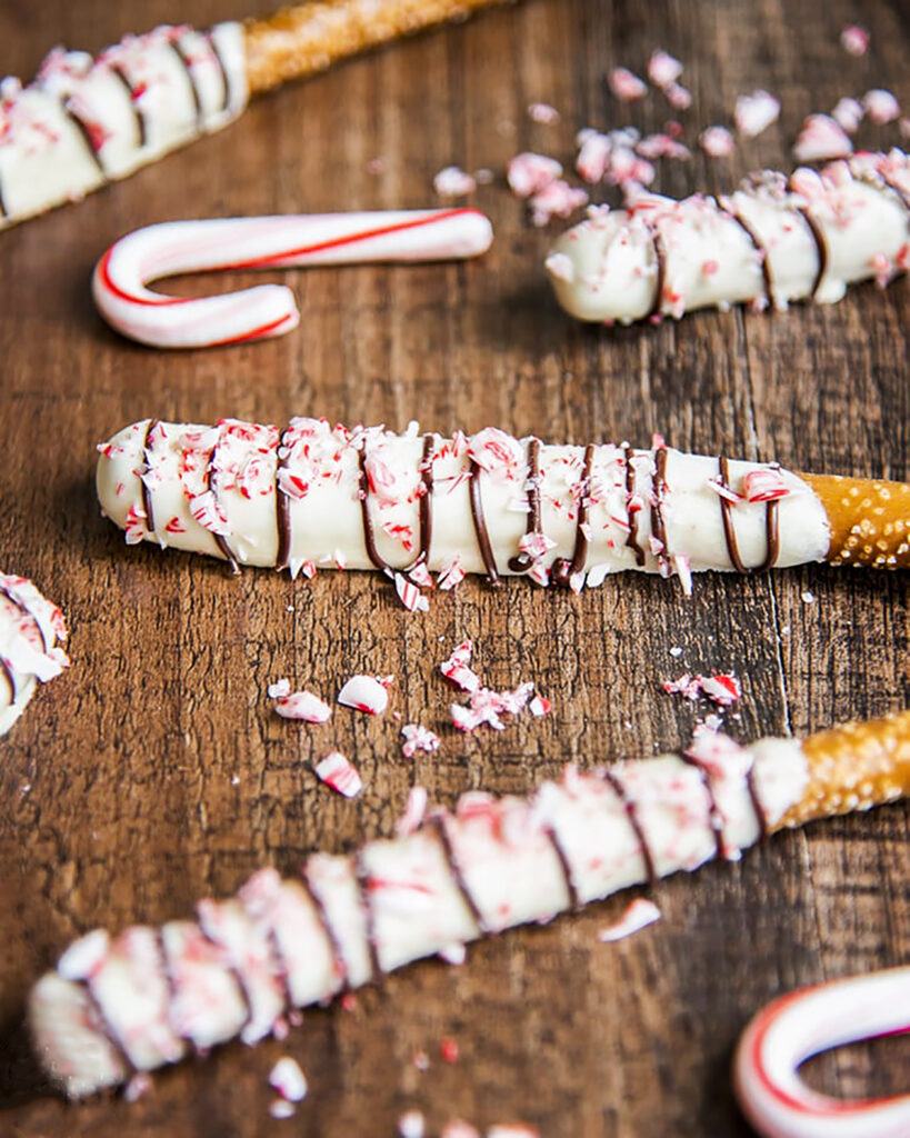 Pretzel rods covered in white chocolate and candy cane pieces.