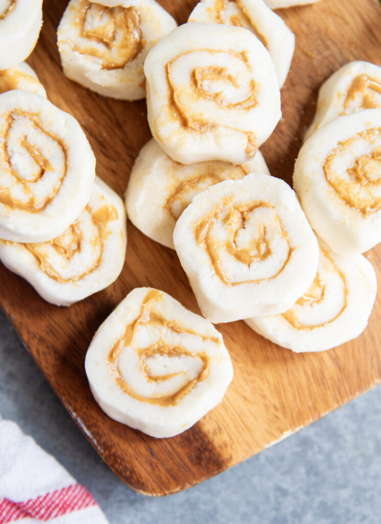 A stack of peanut butter potato pinwheel candies on a wooden board.