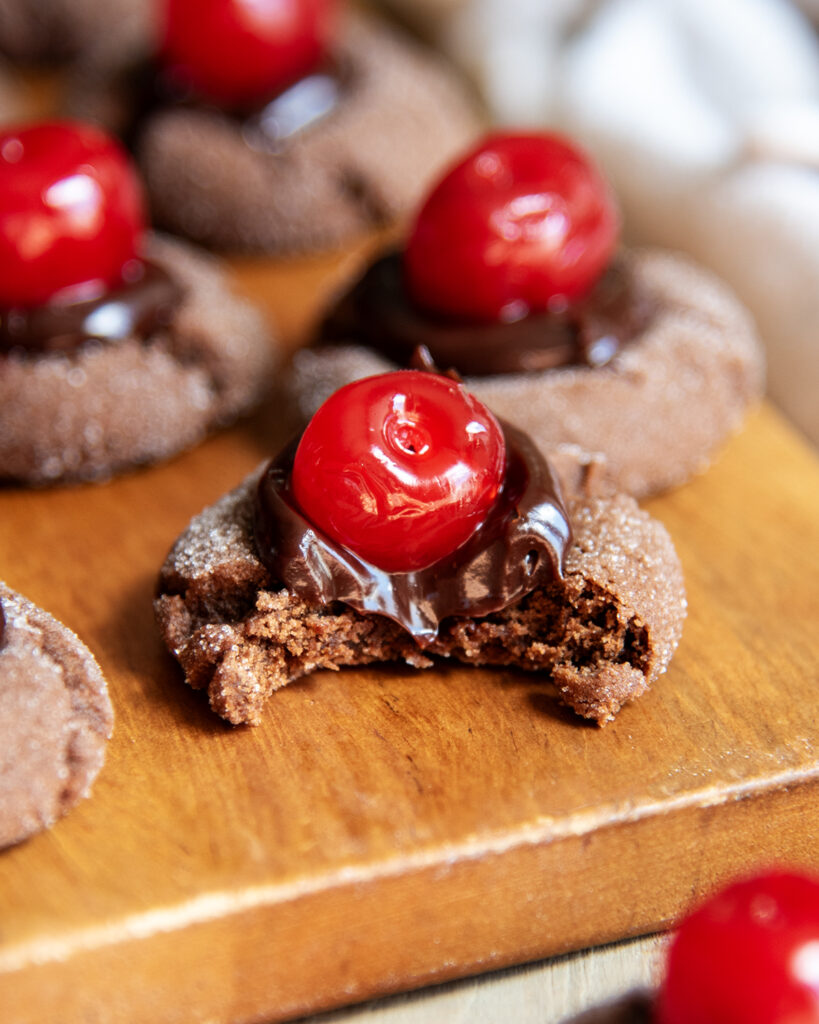 A chocolate cherry cookie with a bite out of it.